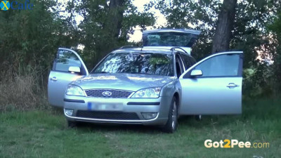 Playful blonde hoe pisses on the hood of a car somewhere in the forest