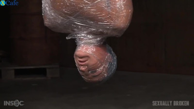 Brunette poor girl wrapped in plastic and suspended upside down