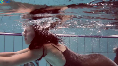 Skinny brunette hot babe in long black dress swimming underwater