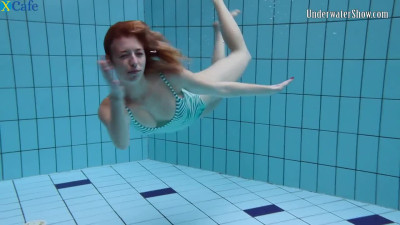 Playful redhead chick Anetta swims naked in the pool