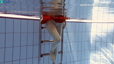 Redhead beauty Ala swims under the water in the pool